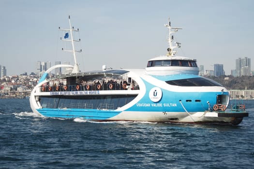 A ferry travels on water with a city skyline in the background.