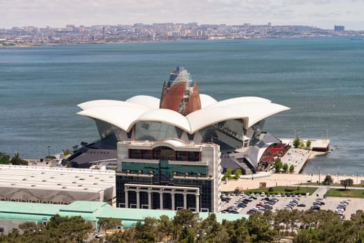 The waterfront view showcases Deniz Mall in the foreground, against a blue sky in Baku, Azerbaijan