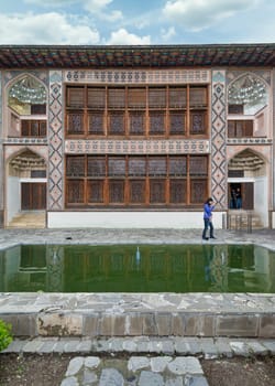 Shaki, Azerbaijan - May 15, 2024: Intricate architecture of Shaki Khan Palace, surrounded by lush greenery and a tranquil reflection pool