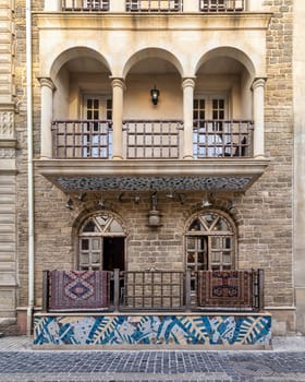 Baku's Icheri Sheher: Cobblestone alleys, stone buildings with arched windows, balconies, and intricate carvings. Vibrant Azerbaijani carpets hang from balconies, adding to its historic charm