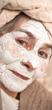 An elderly woman takes care of her health and beauty, applies a cosmetic mask on her face, has a good time, close-up view.