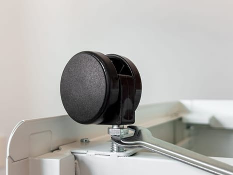 Close up of a black rubber caster wheel on a metal frame with wrench adjustment.