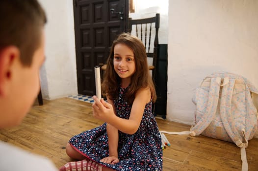 Young girl in a cozy interior interacts while holding a pencil, expressing joy and engagement.