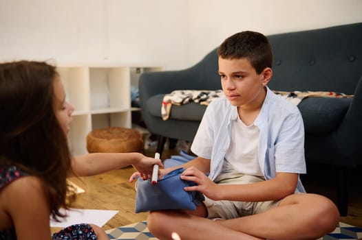 A boy and girl share a moment while sitting on the living room floor, conveying youthful connection.