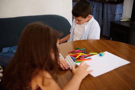 Two children engaging in an arts and crafts activity with colorful markers and paper, fostering creativity and collaboration in a domestic setting.