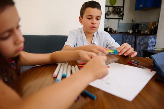 Two young children engaged in a creative art activity at home, surrounded by markers and paper, fostering imagination and fun.