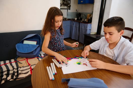 Two children engaging in creative art activities, crafting vibrant pictures on paper, enjoying a fun, hands-on moment. Backdrop shows a cozy interior setting, a school bag resting nearby.