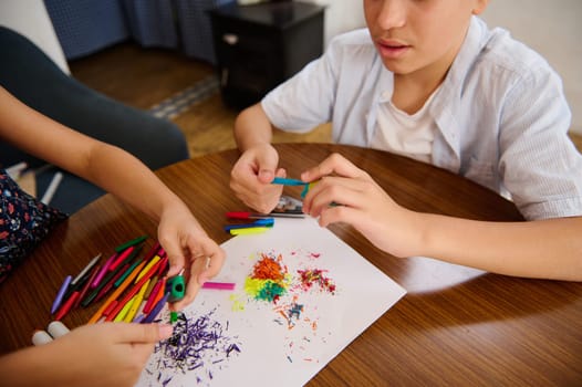 Young children engaging in a creative art project using colorful materials and tools. Their artistic collaboration fosters imagination and hands-on skills development.
