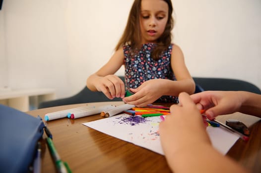 Young children exploring creativity through colorful art supplies on a table during a playful and educational activity session.