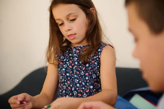 A young girl concentrates on a creative task, showcasing thoughtful expression and a casual setting.