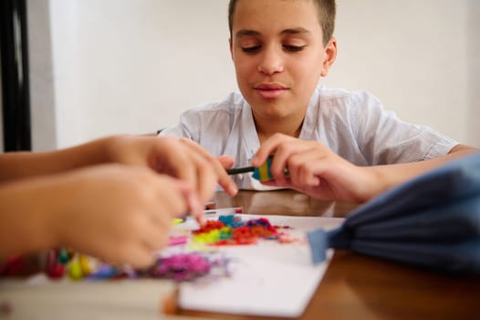 Young boy sharpening colored pencils while sitting at a table, engaging in creativity.
