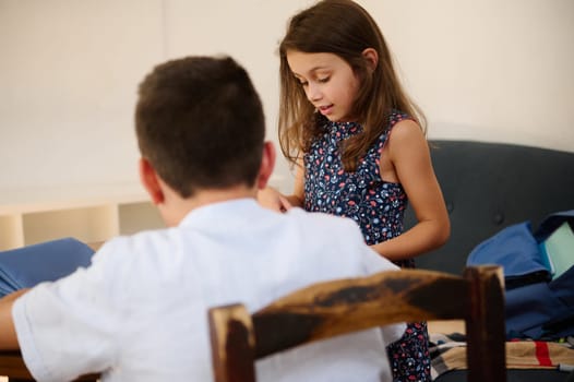 Two children are indoors, engaged in a collaborative activity at a table, with focus and involvement evident. Their interaction conveys teamwork and curiosity during their shared task.