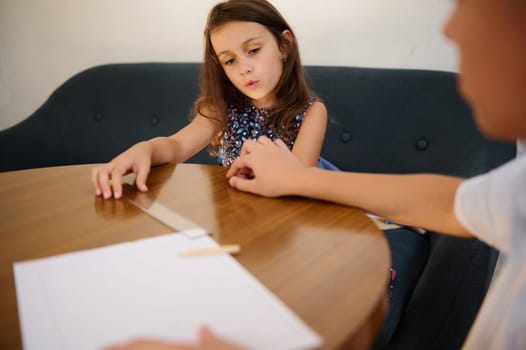 A young girl participates in an activity at home, focused on learning. A casual and informal educational scene.