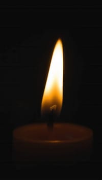 Burning candle on a dark background. Shallow depth of field