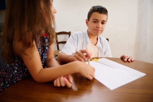 Two children working collaboratively at a table, engaging with a paper activity.
