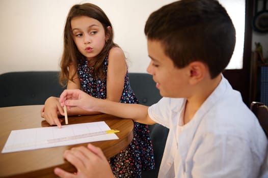 Two children working together on an assignment at a table, showcasing teamwork and education.