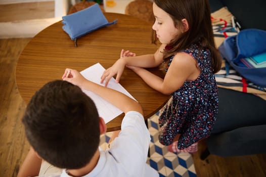Two children are engaged in learning or homework around a table, fostering collaboration.