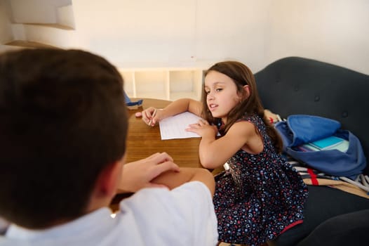 Two children collaborate on their homework at a wooden table, fostering learning and teamwork.