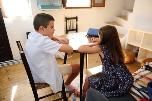 Two siblings enjoying a relaxed moment together in a cozy indoor space, capturing a sense of togetherness and bonding in a cheerful home environment.