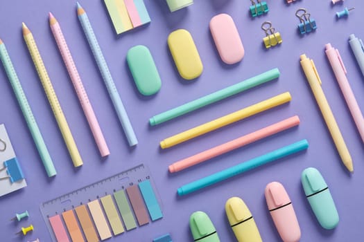 Stationery background with pastel-colored stationery neatly arranged on a light purple background.