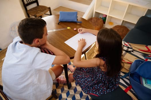 Two children collaborate on a study task at a wooden table, fostering teamwork and education.