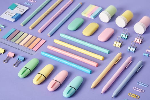 Stationery background with pastel-colored stationery neatly arranged on a light purple background.