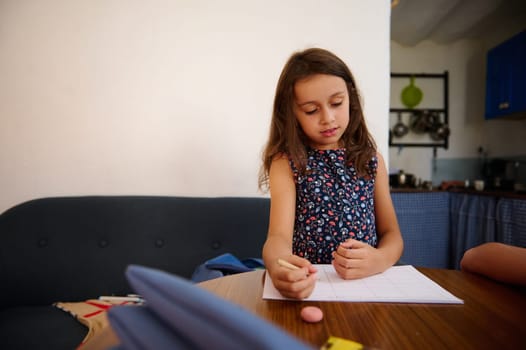 A young girl sitting at a desk in a room, engaging thoughtfully with her school assignment. She appears focused and engaged, promoting education and creativity in a cozy domestic setting.
