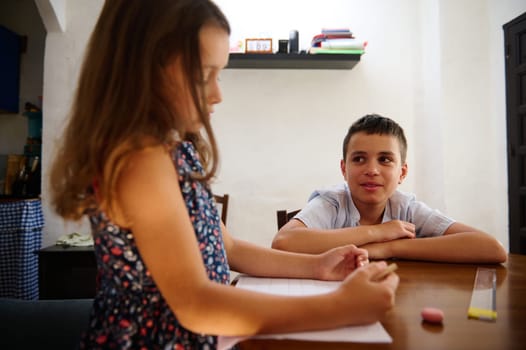 A young boy and girl are engaged in an activity, seated at a table in a well-lit room, fostering a sense of interaction and teamwork.