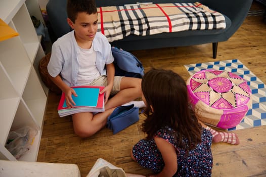 Two kids sorting school supplies in a cozy living room, preparing for activities.