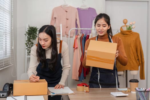 Two diverse female e-commerce employees preparing packages for shipment while organizing inventory in a retail store.