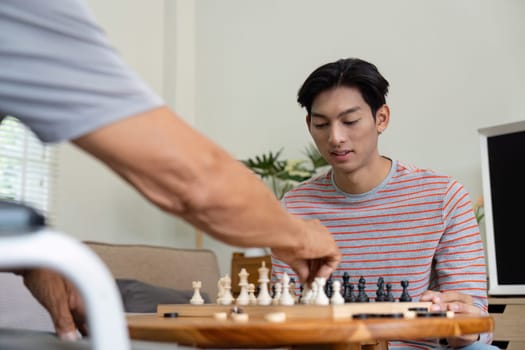 A young man attentively watching his father make a move during a chess game, highlighting their family interaction and shared enjoyment.