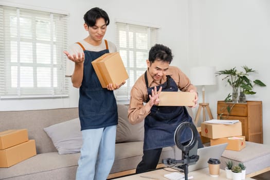 Two dynamic social media marketers presenting and showcasing product packages to their online audience during a vibrant live stream in a cozy home office.