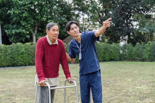 A young caregiver assists an elderly man with a walker, pointing at interesting sights in a vibrant garden, fostering connection and encouraging mobility.