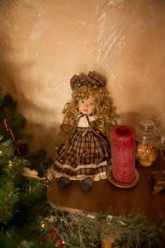 Cute vintage doll sits on a shelf near a Christmas tree. The doll is dressed in a dark red velvet dress.