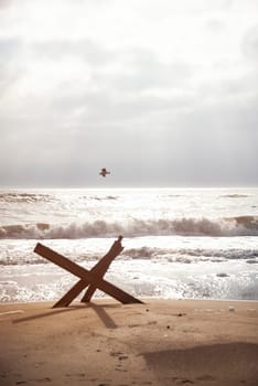 seascape with beach and iron fortification on the beach. sea horizon, flying seagulls. antitank fortification stands on sea sand. fortification from enemy landing in Ukraine on Odessa beach