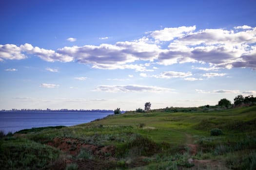 the path goes through a grassy landscape. the sea is on the horizon. the city is visible in the distance