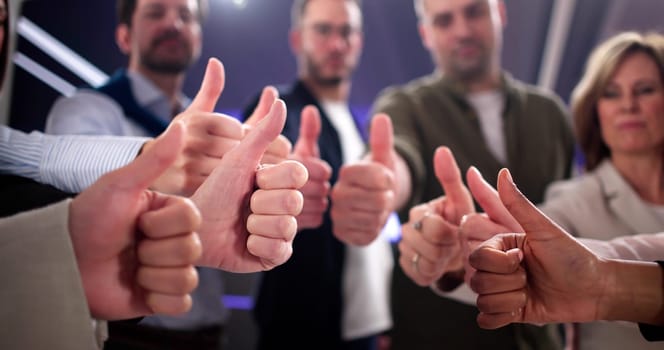 Smiling business team gives thumbs up for successful deal.