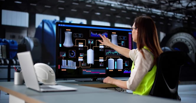 Young female engineer operates SCADA system at oil refinery power plant.