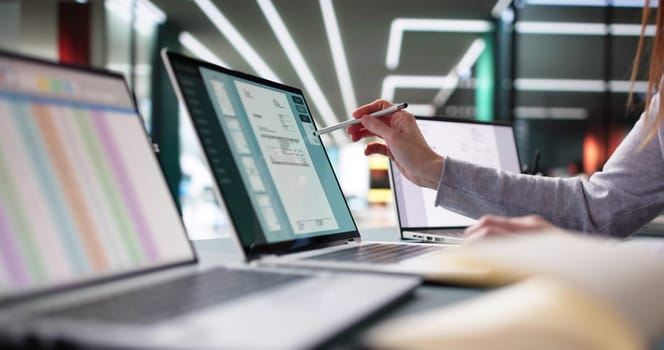 Young female accountant managing e-invoices on laptop in office setting.
