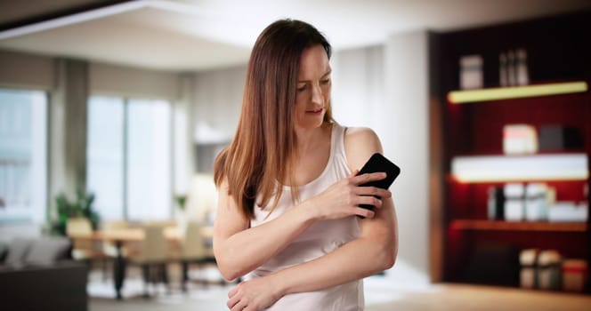 Young woman checking her blood sugar levels with a smartphone.