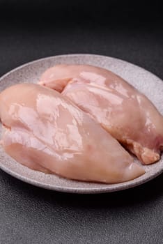 Raw chicken or turkey fillet with salt, spices and herbs on a dark concrete background