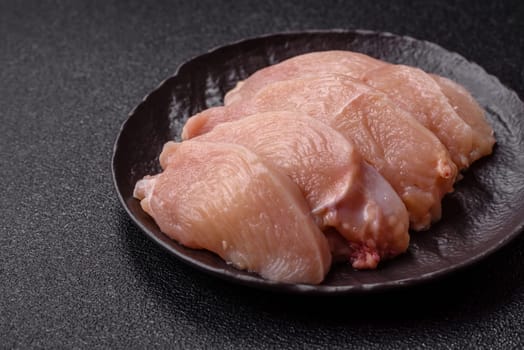 Raw chicken or turkey fillet cut into slices with salt, spices and herbs on a dark concrete background
