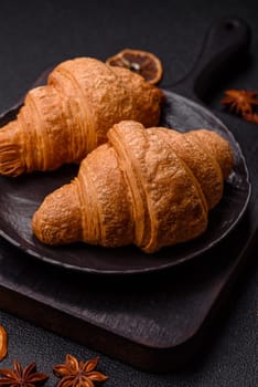 Sweet crispy croissants with chocolate filling on a dark concrete background