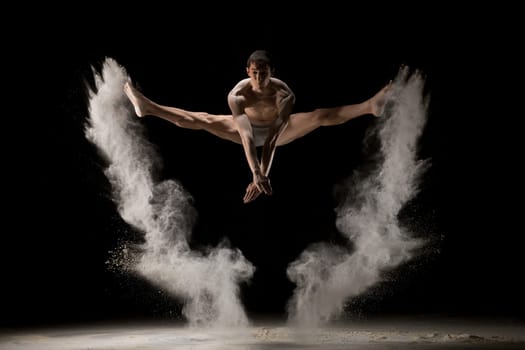 Male gymnast jumping in white dust cloud view