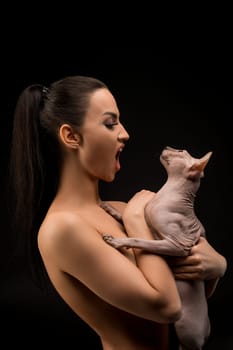 Nude girl with sphynx cat cropped profile portrait in the dark