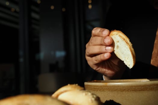 A hand reaches for a slice of bread to dip into a flavorful sauce.