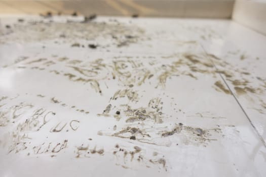 Creative marks and patterns made on a grimy white surface indoors.