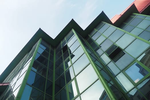 Unique building with angular design and green glass reflecting sunlight.