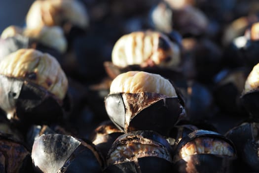 Freshly roasted chestnuts are piled together at a market stall.
