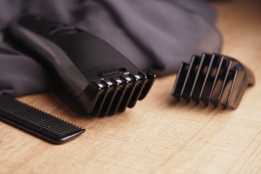 Modern hair trimmer with guard and comb placed on a wooden table.